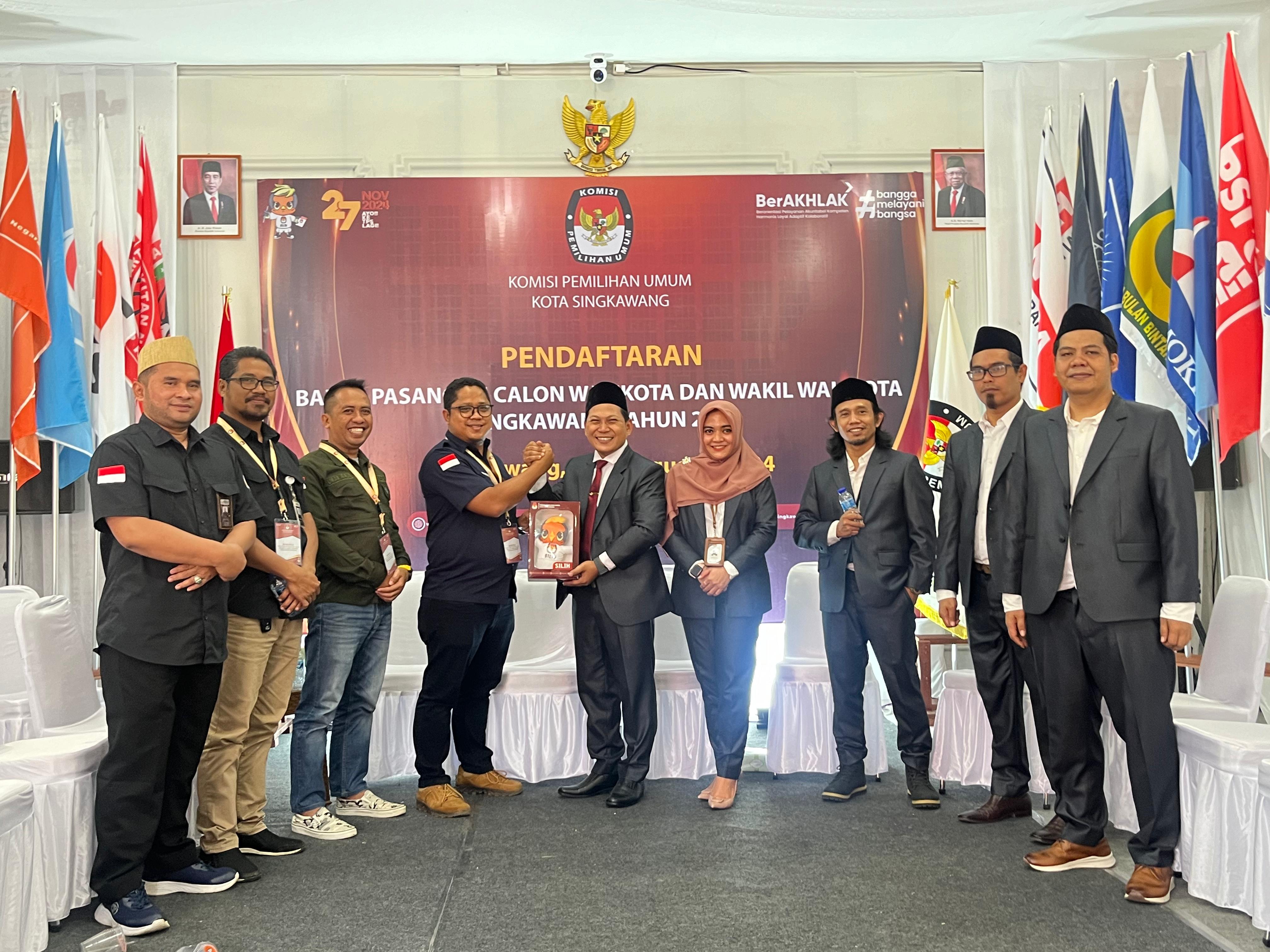 Ketua KPU Kota Singkawang menyerahkan cinderamata berupa maskot Pilkada kepada Ketua Bawaslu Kota Singkawang. ( Rabu 28/8 )